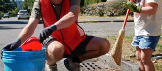 An adult and child cleaning a storm drain.