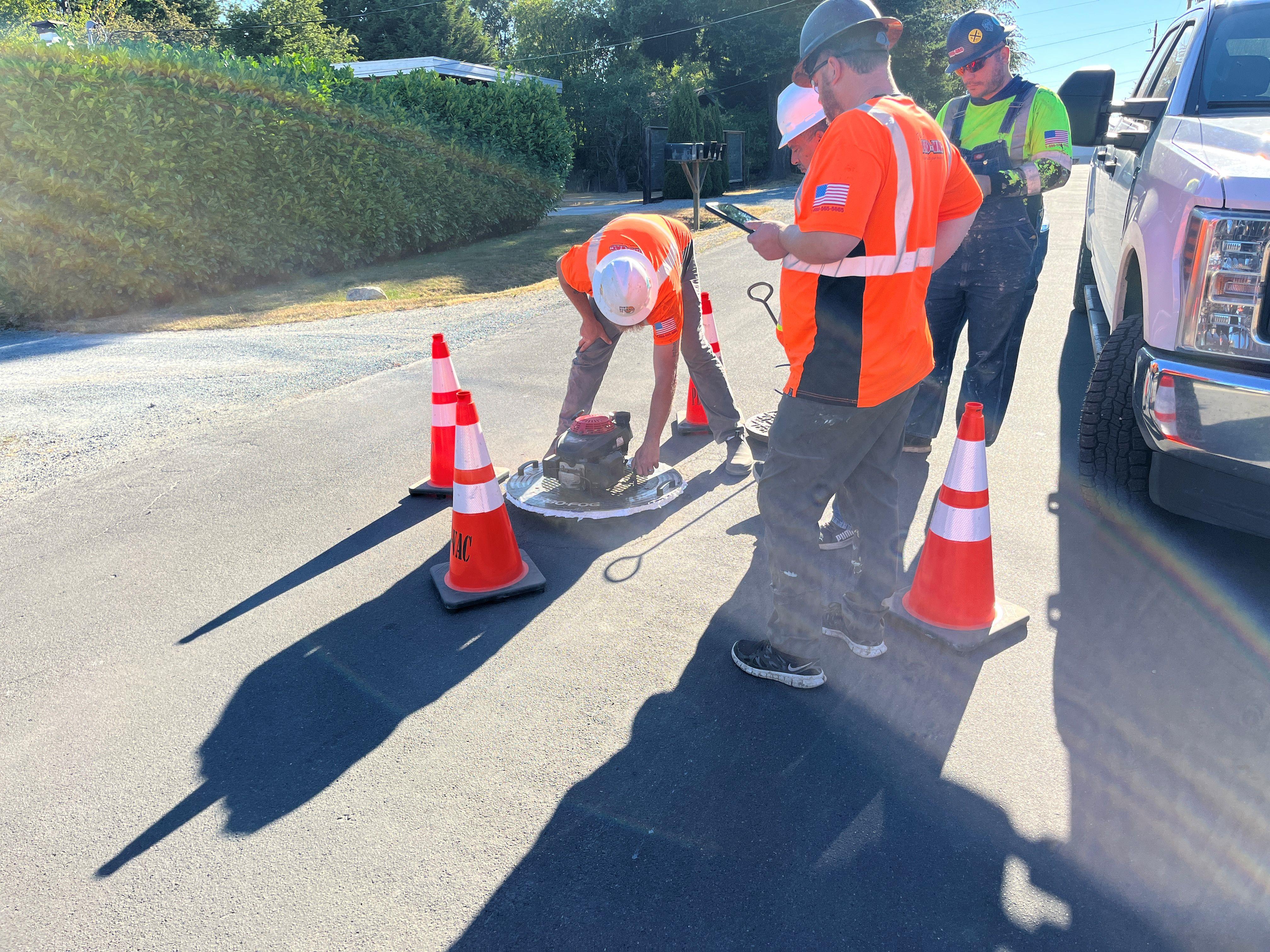 An utility crew at a maintenance hole doing water vapor testing.
