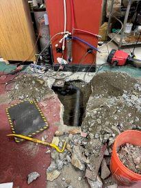 Una secci&oacute;n de piso levantado con una tuber&iacute;a expuesta debajo del concreto 