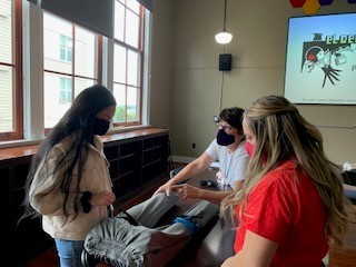 Two students learning how to control bleeding from their instructor