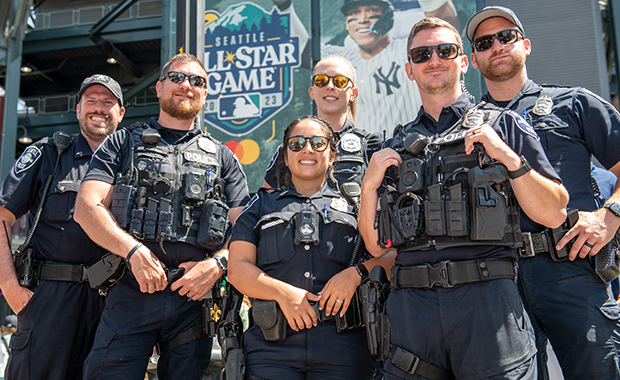 Group of diverse SPD officers standing in front of stadium and smiling