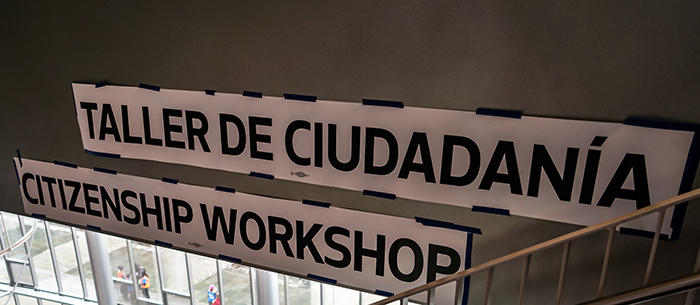 Two long paper signs taped to the walls of a stairwell at a City of Seattle Citizenship Mega-workshop. On the signs are these words: "Citizenship Clinic" and "Taller de Ciudadania."