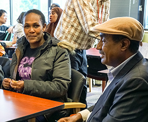 Two Ready to Work graduates from the African immigrant community are seated at a table smiling.