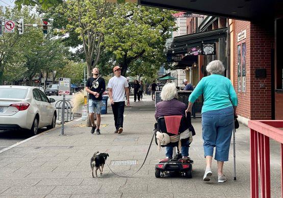 Friends walking and rolling along the sidewalk of NW Market St in Ballard