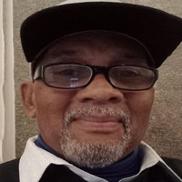 Black man with glasses and grey beard wearing a hat