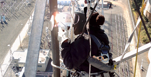 Worker welds equipment high above the ground