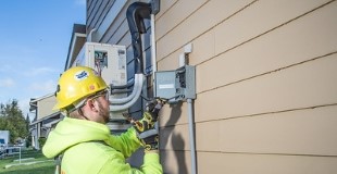 Construction worker, Joshua Burrell, reconfigures the wiring for newly installed heat pumps outside residents' homes. Source: https://www.flickr.com/photos/eeimagedatabase/32943799805/