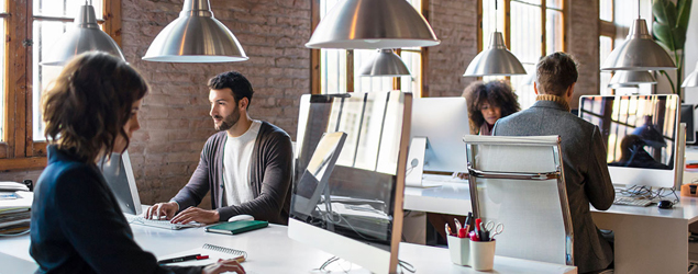 Modern office setting with open floorplan and several workers at computers