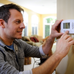 Man Programming Thermostat Photo - Source: Consumers Energy https://www.flickr.com/photos/eeimagedatabase/28893113890/