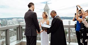Image of a couple getting married in front of a judge with Seattle City Skyline in the background