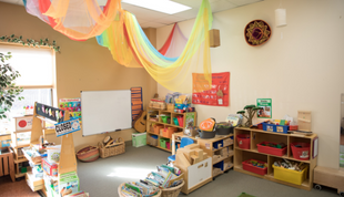 Image depicts a high-quality early learning environment with colorful toys and learning stations.