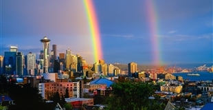 A double rainbow stretching over the Space Needle and the Seattle skyline on an overcast day