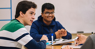 Young men talk around a table