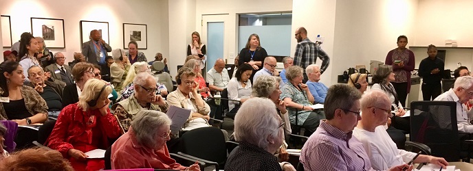 An audience of older adults waits for an event to begin