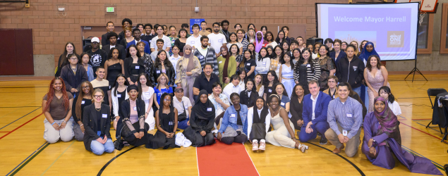 Youths, male and female, and of different races, gathered together in a gym with the Mayor and other City and community leaders at the 2024 Summer Internship celebration