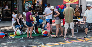 Street fair outreach with street chalk, bouncy balls, and people playing games with City staff.