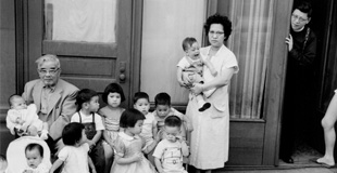 Black and white photo of a family sitting on a stoop in Chinatown in Seattle.