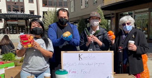 Four volunteers holding up food donations for members of the public.