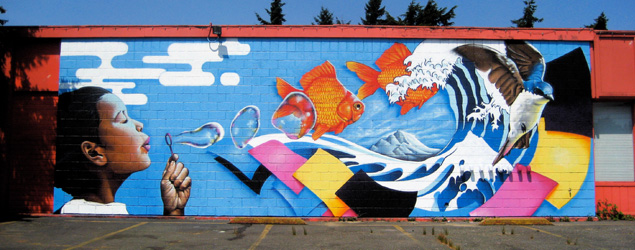 Mural of a young person blowing bubbles that turn into waves and fish and bright colored papers