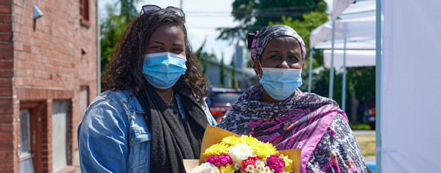 Two Black women holding beautiful flowers.