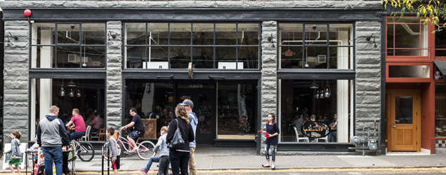 Storefront in historic Ballard with people playing in the street in front of the building.