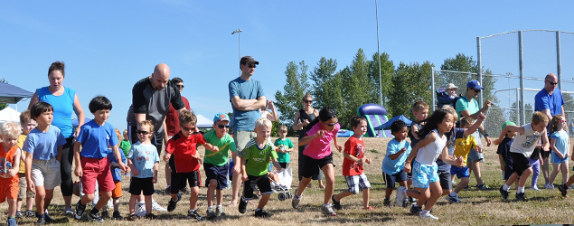 A group of children with a few adults, lined up on a playground for a foot race