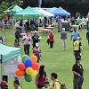 Pop-up festival tents cover a green field, while visitors roam among them