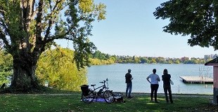 Three people stand look across a lake on a summer day