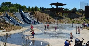 A spray park on a summer day, with children splashing through the fountains.