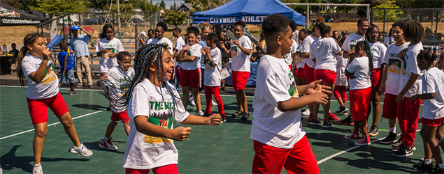 Kids in red shorts dancing on a sports field