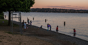 People wading in Magnus Park Beach at dusk