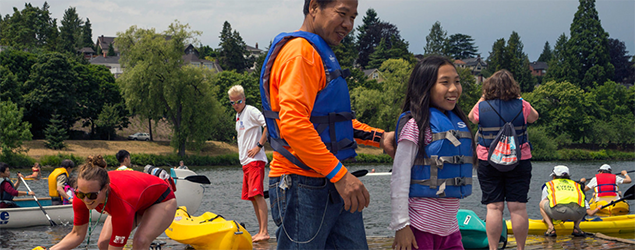 Happy people wearing floatation vests getting ready to go kayaking 