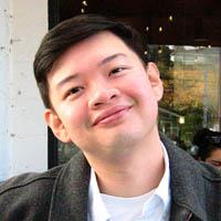 Khanh is smiling and tilting his head to the left, with short hair, wearing white t-shirt and black jacket.