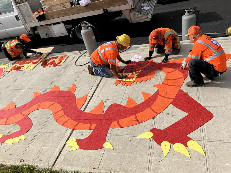 Crew installing a dragon decal, designed by Lawrence Augustine