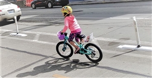 A school age girl rides her bike in a bike lane in downtown Seattle.