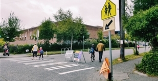 A white and orange barrier sits on a street with signs that say "Street Closed" and "Local Access Only"