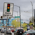 A 'photo enforced' sign along the road that has cards