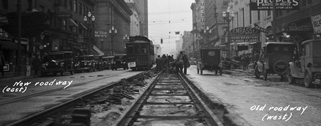 black and white photo of an old seattle street with a railroad down the center
