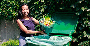 Smiling woman emptying compost into a bin.