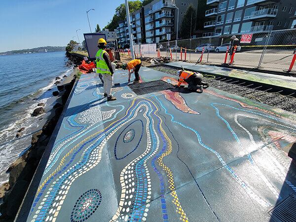 Workers putting finishing touches on the artwork, looking east.