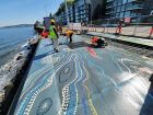 Workers putting finishing touches on the artwork, looking east.