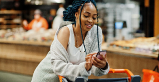 Girl looking at her phone while leaning on a grocery cart