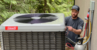 Man standing next to a house working on a heat pump