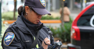 Parking attendant standing near cars writing a ticket