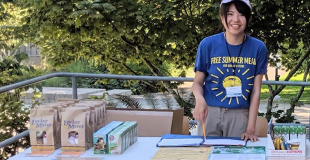 Girl smiling and standing at a table with bagged meals on it