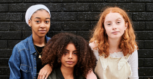 3 young women looking at camera with black background