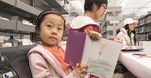 Young child holding a book in a library