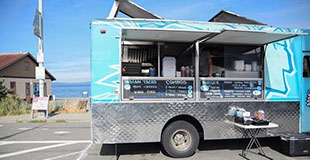 A food truck is parked by the shoreline