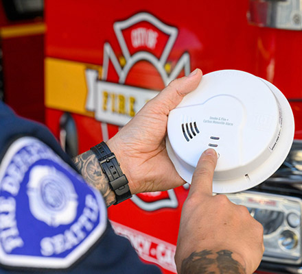 A fireman demonstrates how to check a smoke detector