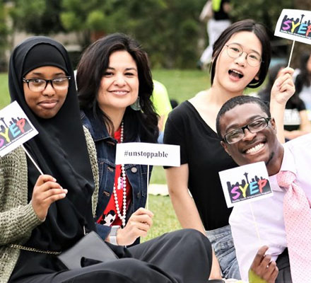 Youth hold up program signs in a park
